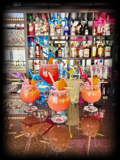 Cócteles rosas y limonadas frente al botellero iluminado