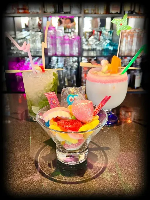 Cócteles en copa martini decorados con golosinas y sombrillas