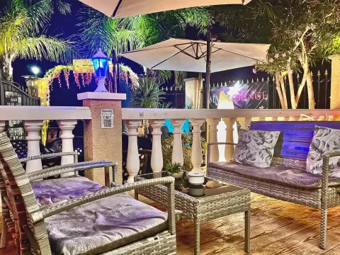 Rincón chill-out nocturno con sofás de mimbre y jardín iluminado