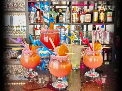 Ronda de cócteles artesanales con adornos tropicales en la barra