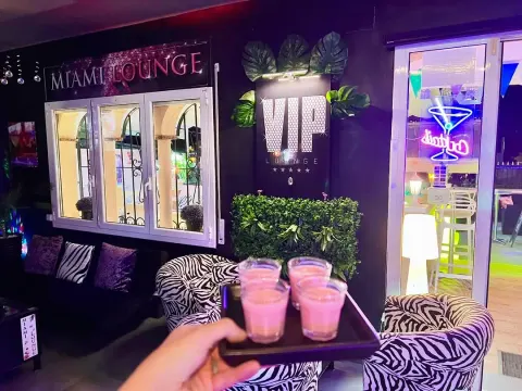 Zona VIP de noche con sofás y bandeja de cócteles rosas